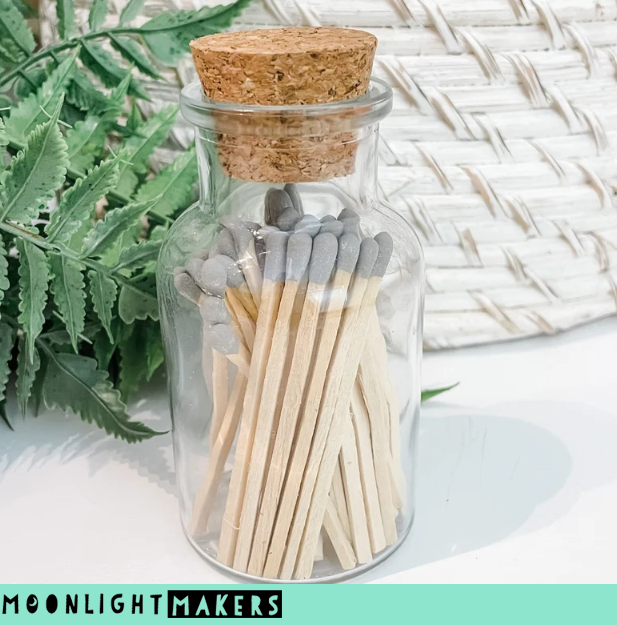 a glass jar filled with matches next to a plant