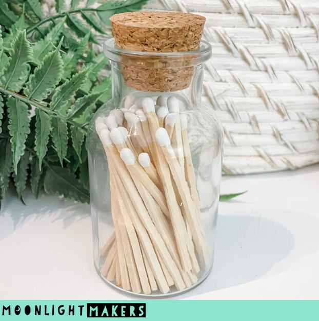 a jar filled with matches next to a plant