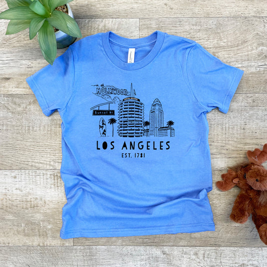 a blue los angeles t - shirt sitting on a wooden floor next to a teddy
