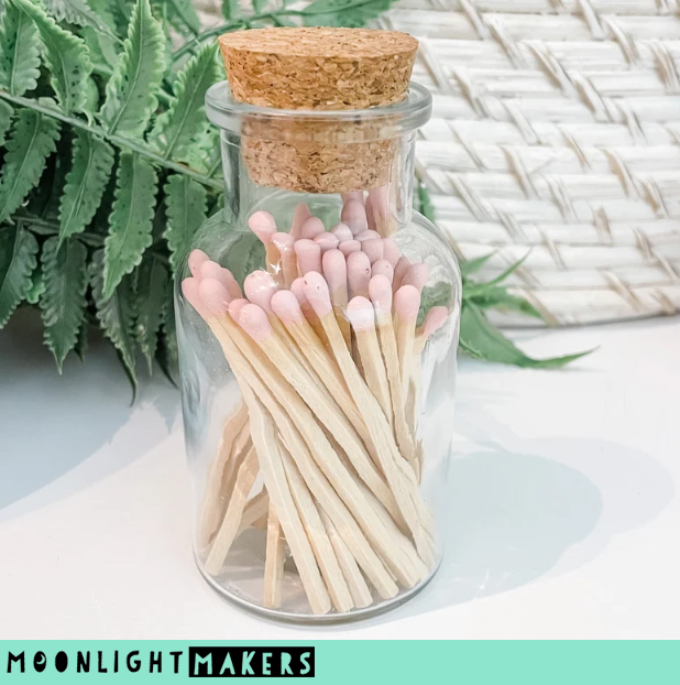 a jar filled with matches next to a plant
