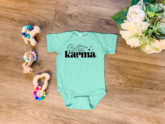 a baby's bodysuit with the word karma written on it