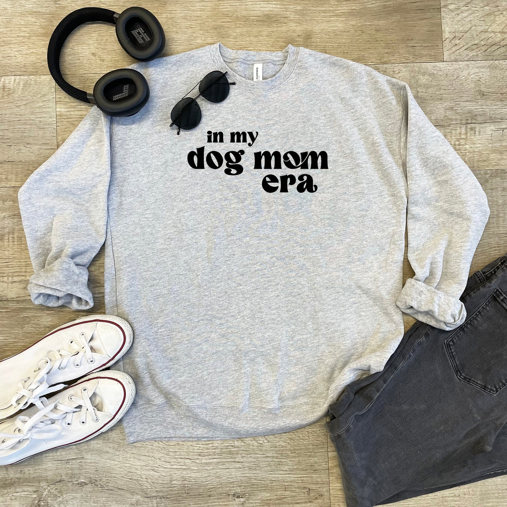 a sweatshirt that says in my dog mom era next to headphones