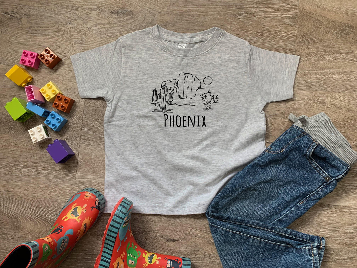 a t - shirt with a picture of a dinosaur on it next to a pair