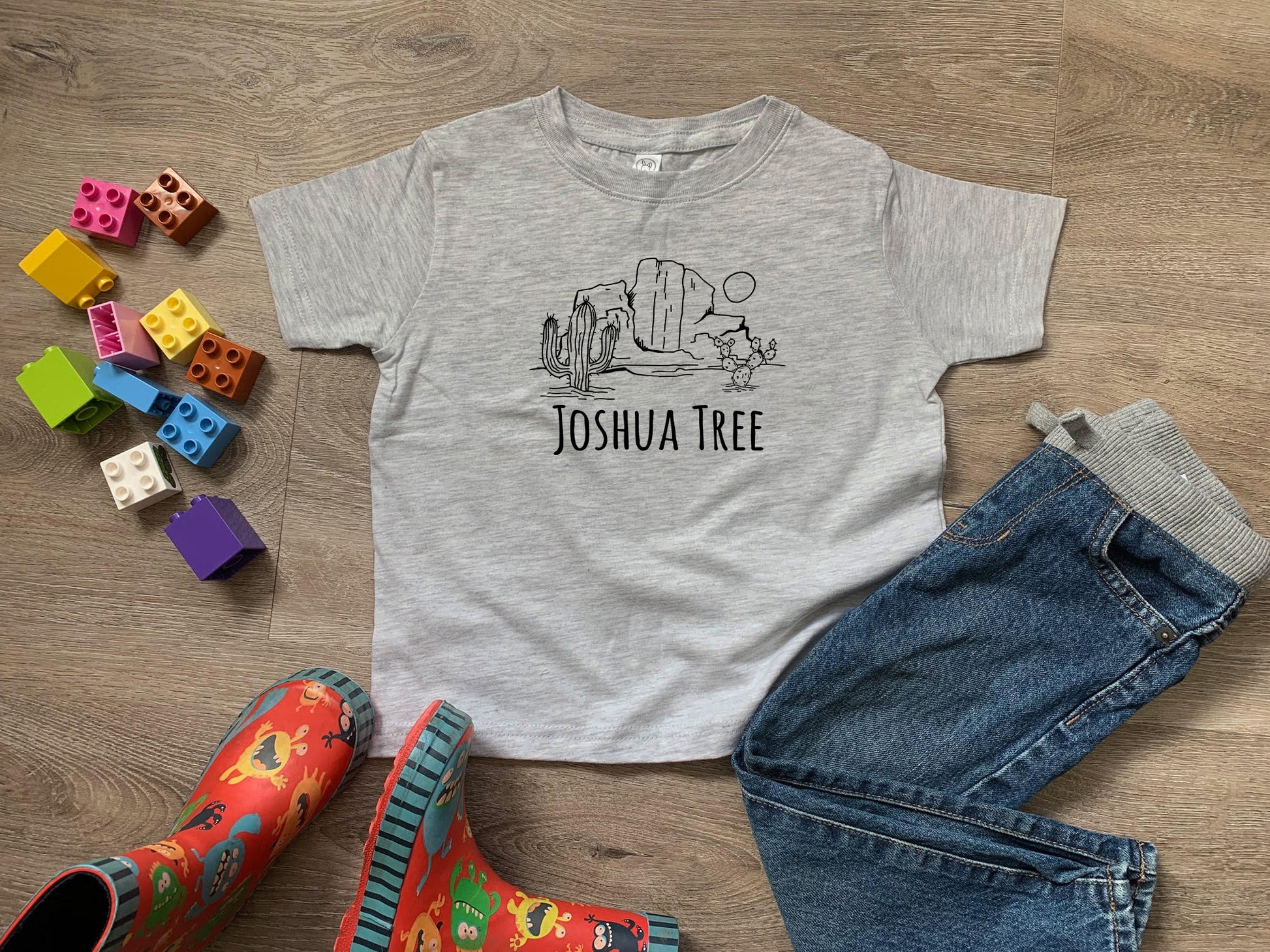 a t - shirt that says joshua tree next to a pair of jeans and rubber