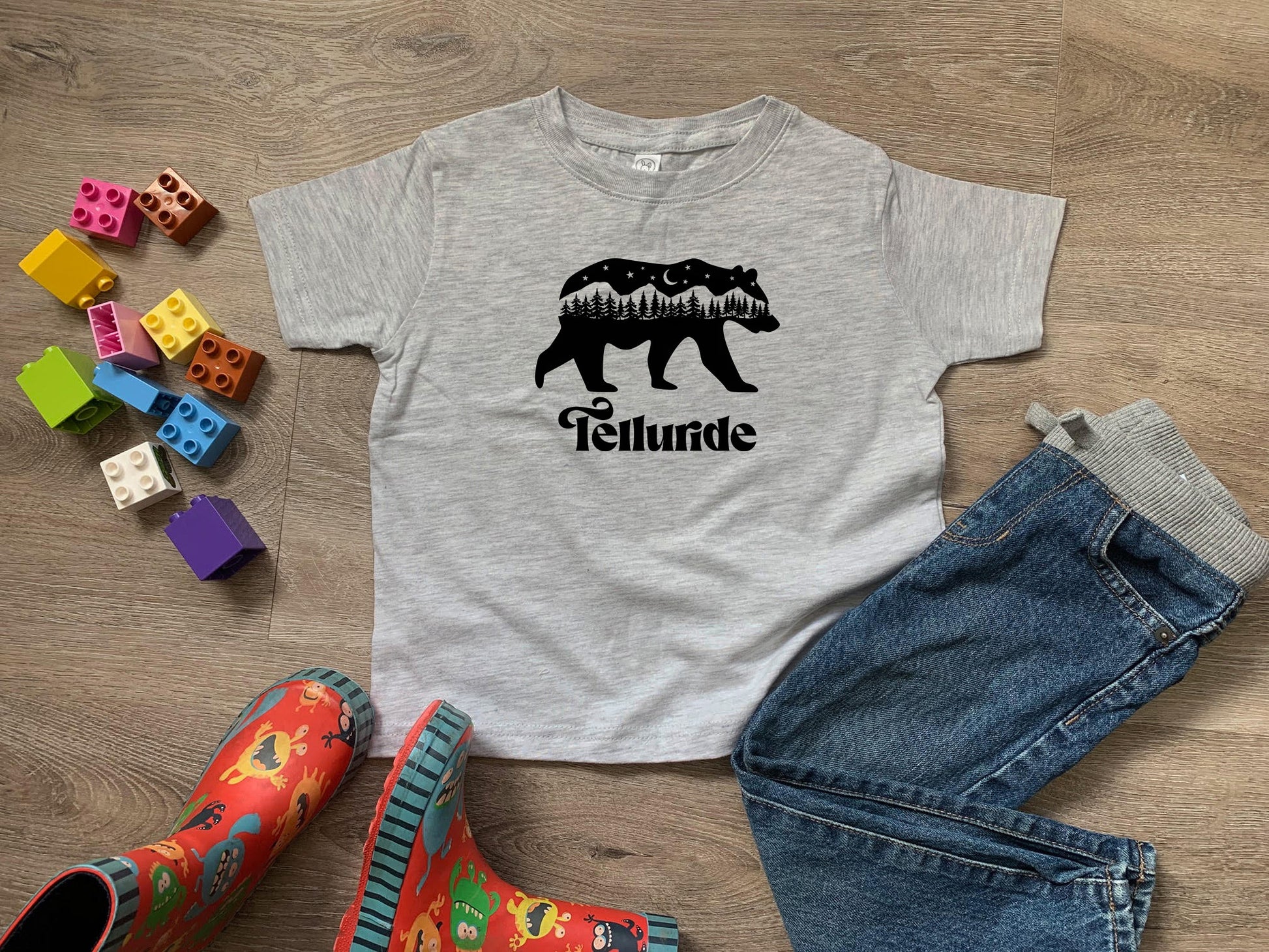 a t - shirt with a bear on it next to a pair of jeans and