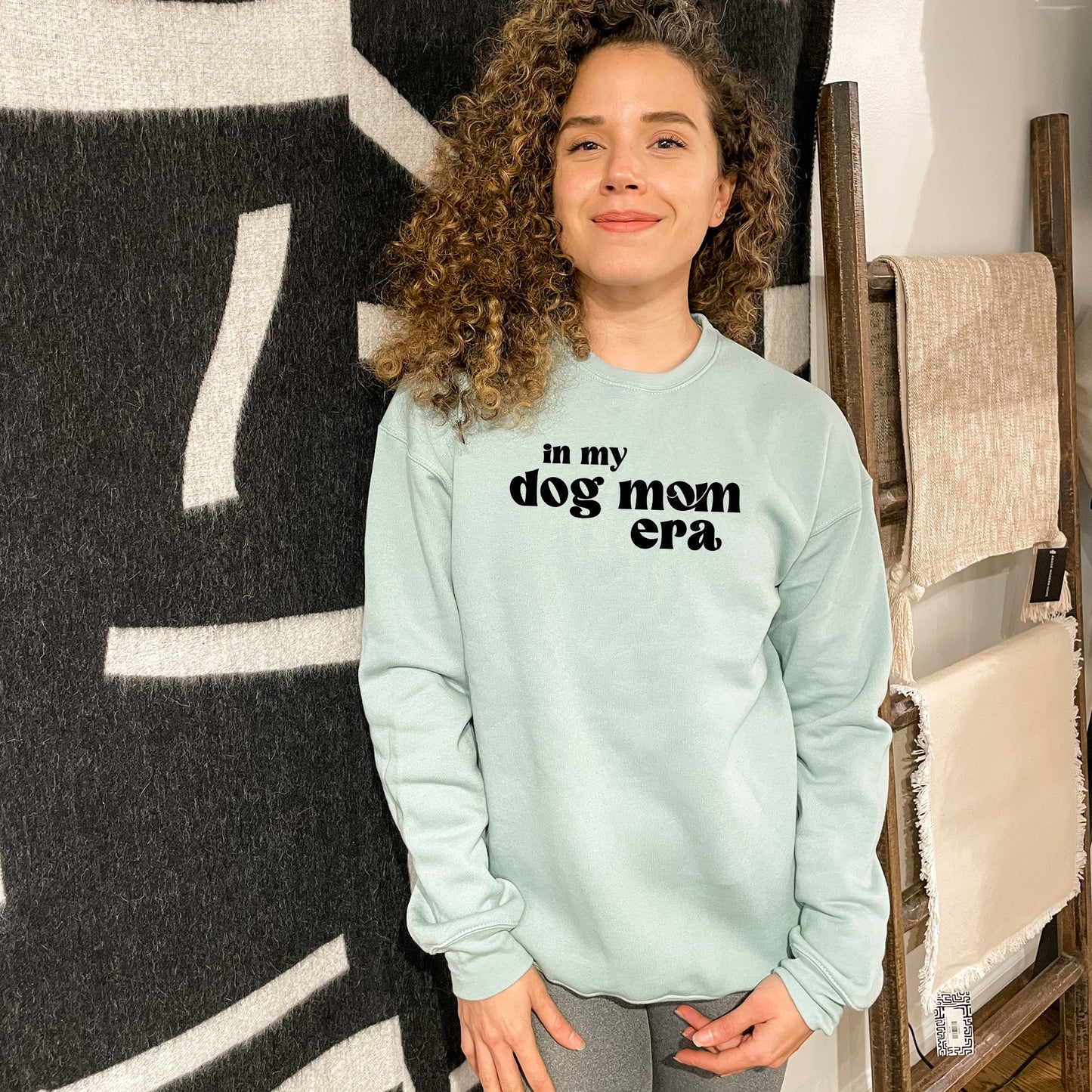 a woman standing in front of a wall with a dog mom on it