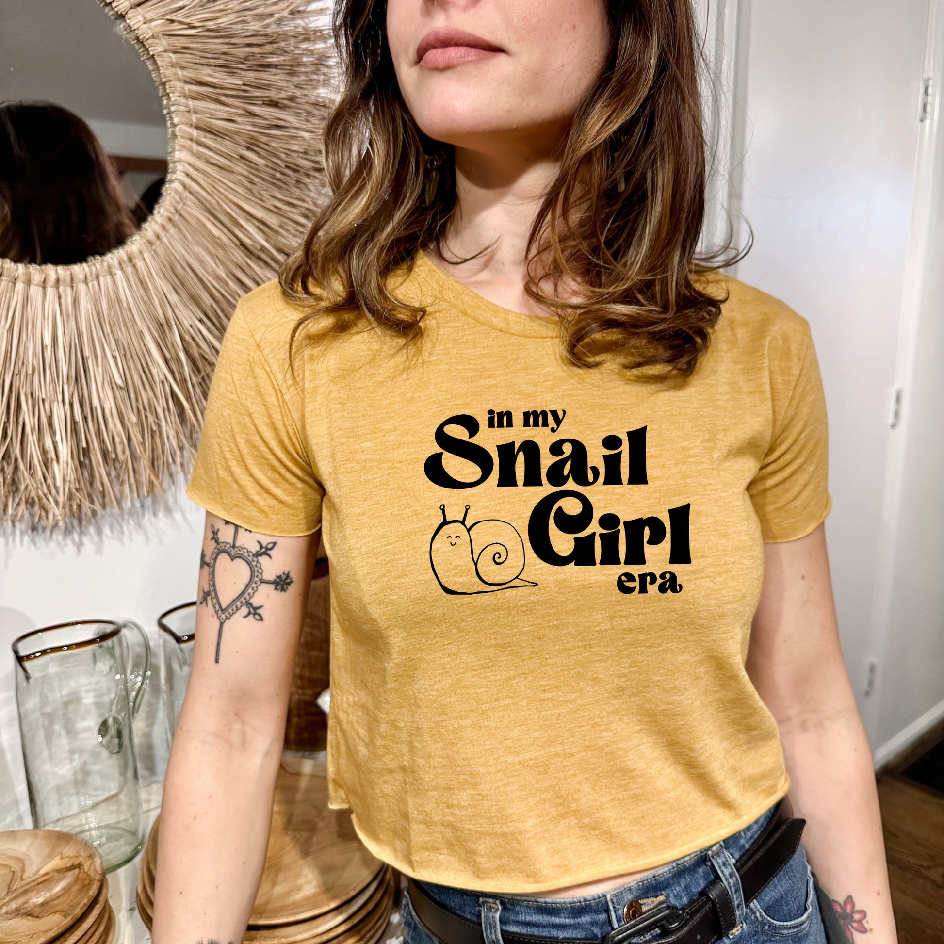 a woman wearing a yellow shirt with a snail girl on it