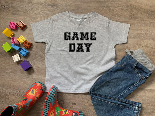 a t - shirt that says game day next to a pair of jeans and rubber