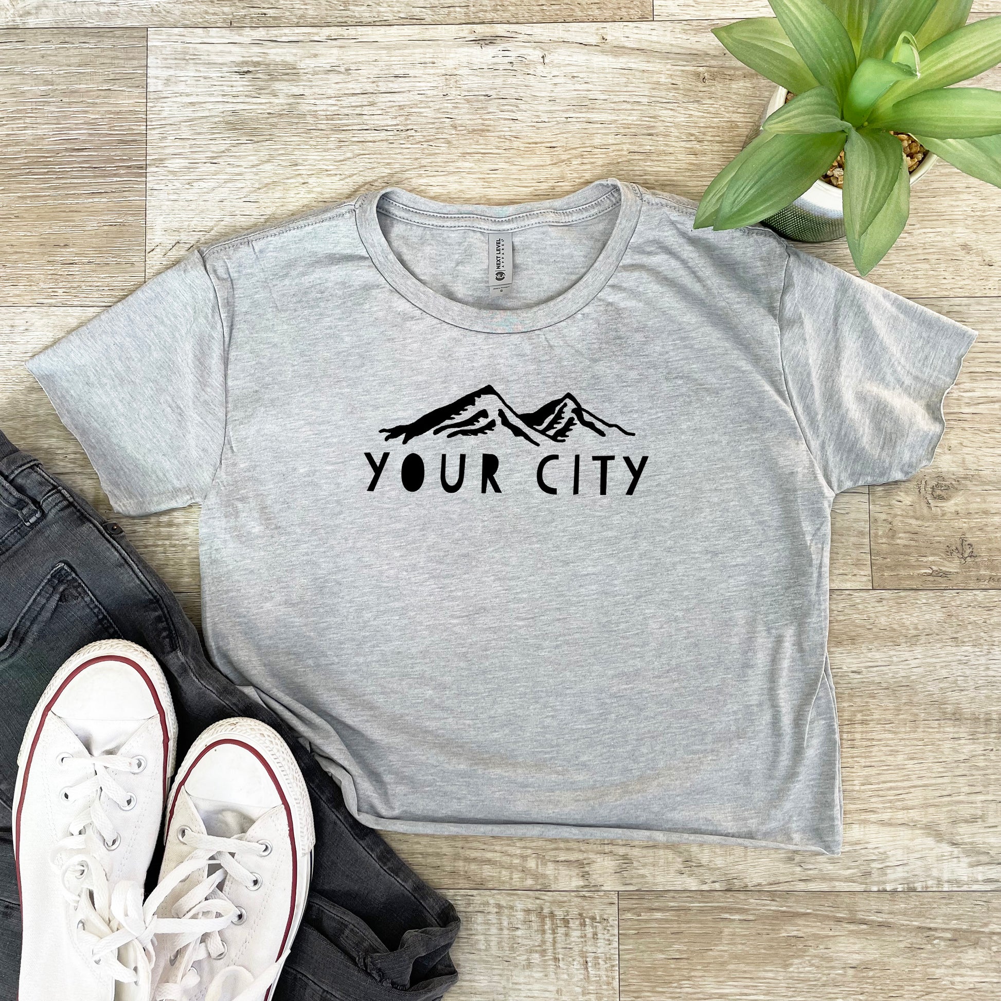 a t - shirt with the words your city on it next to a pair of