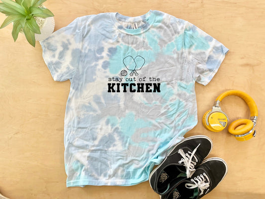 a t - shirt that says stay out of the kitchen next to headphones and