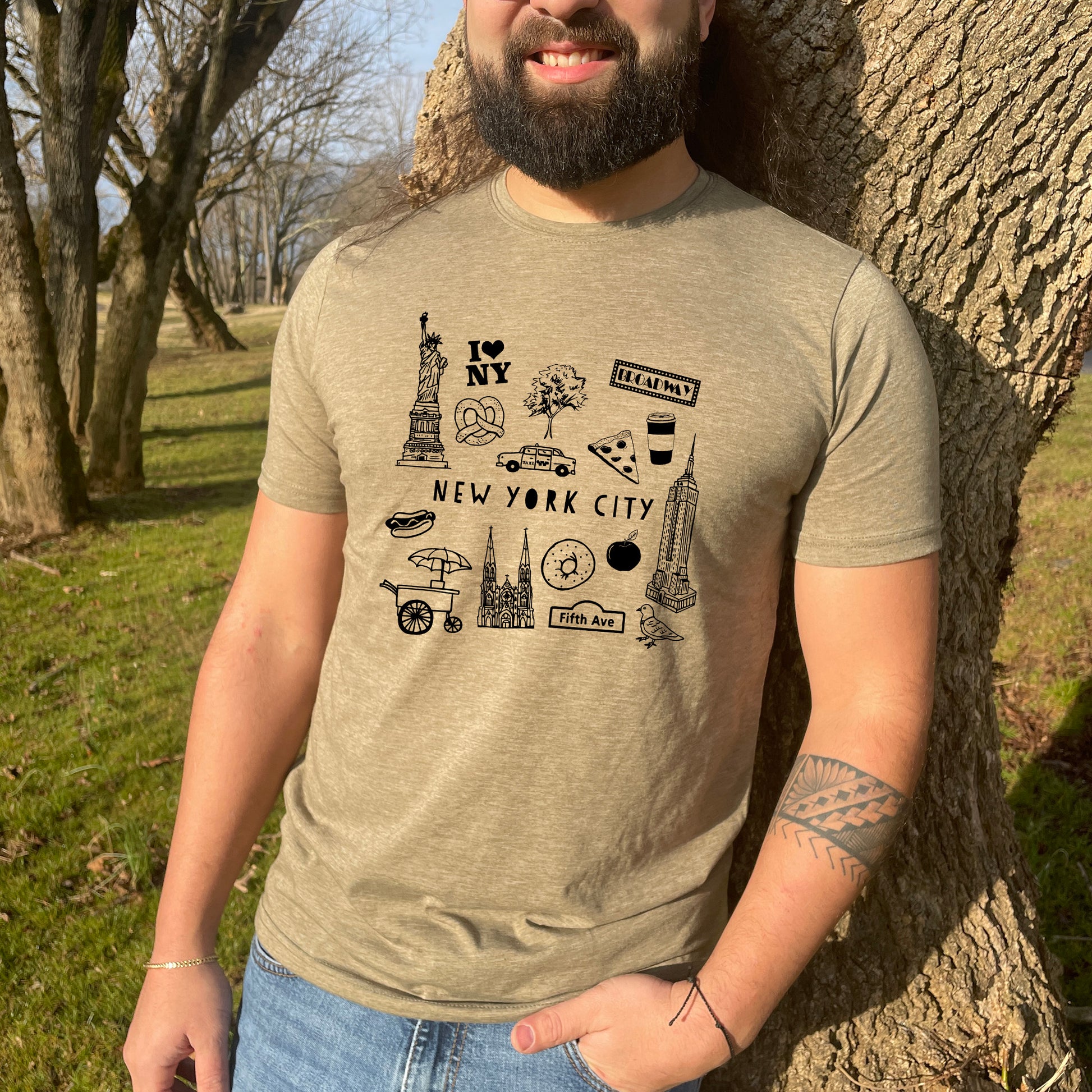 a man standing in front of a tree wearing a new york city t - shirt