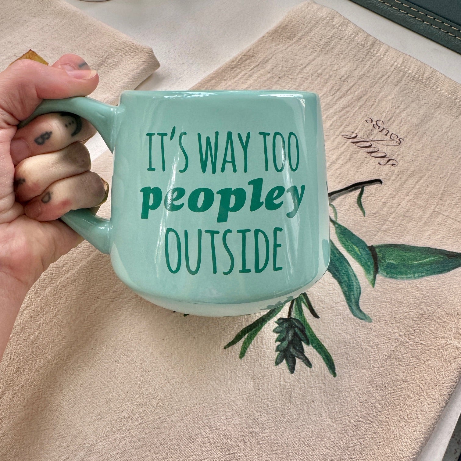 a person holding a coffee mug that says it's way to people outside