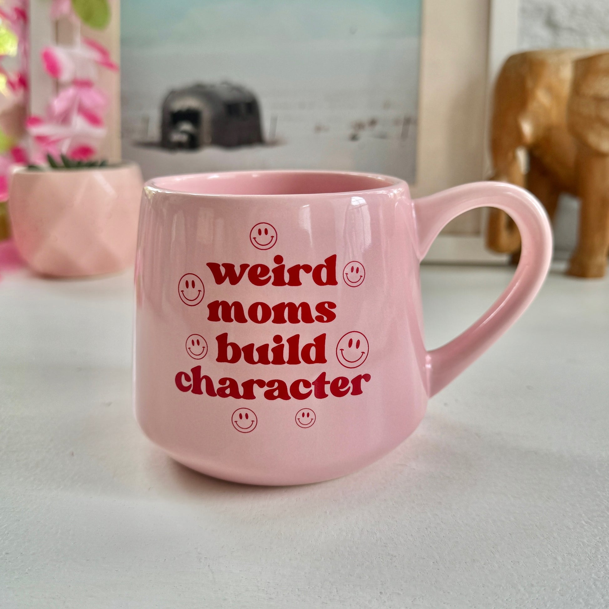 a pink coffee mug that says weird moms build character