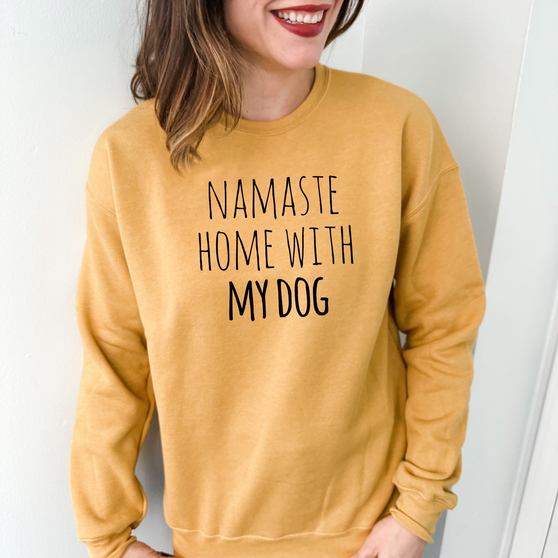 a woman wearing a sweatshirt that says namaste home with my dog