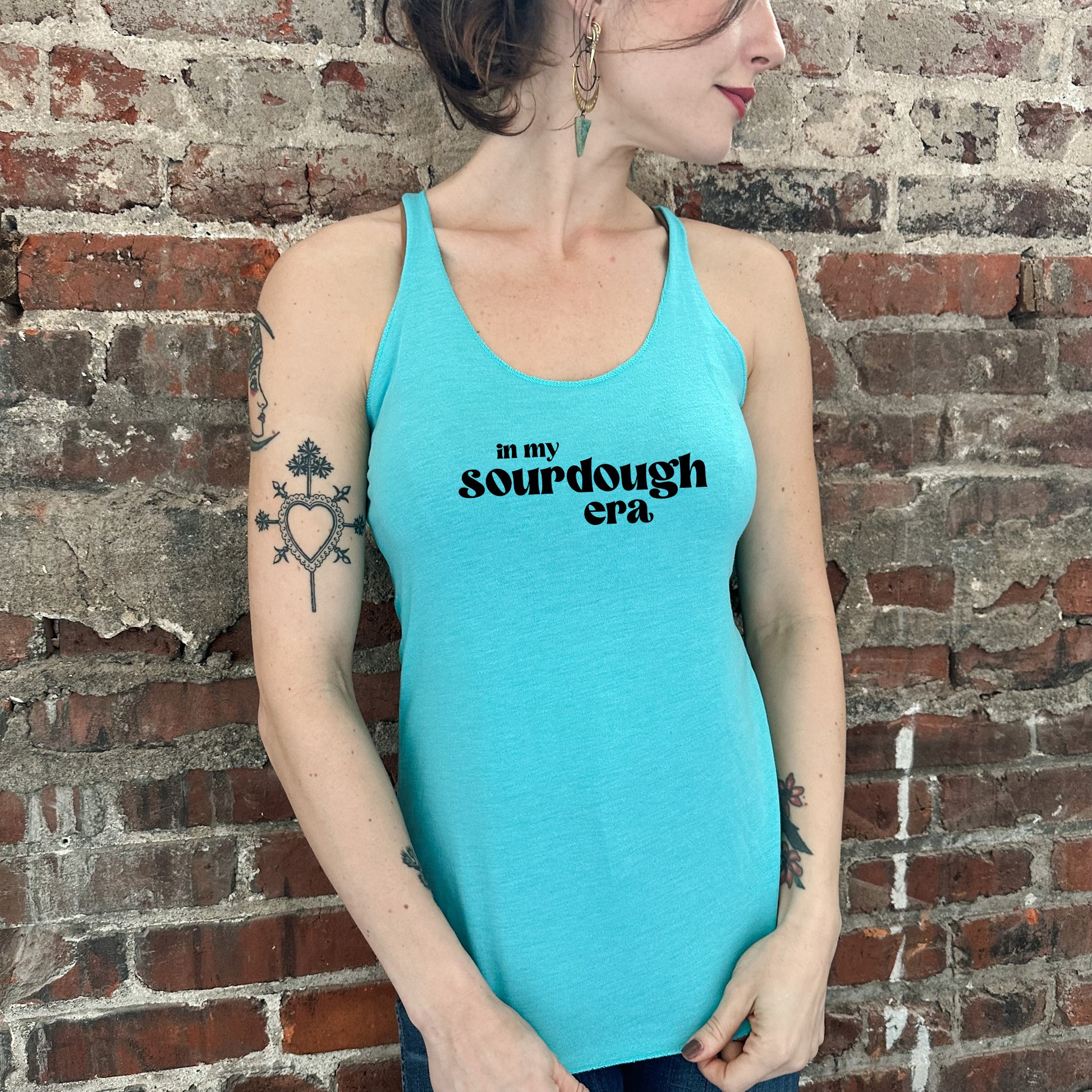 a woman wearing a blue tank top with a tattoo on her arm