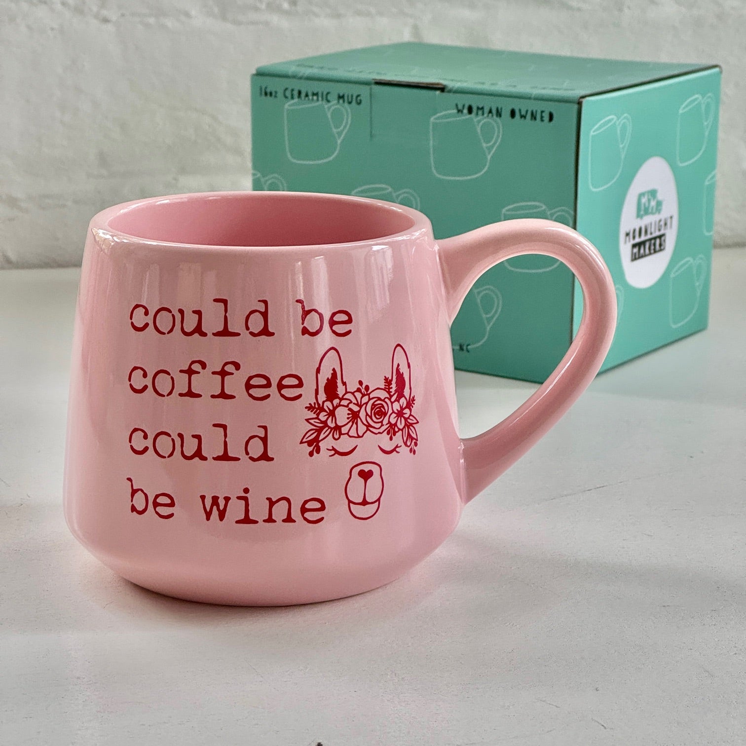 a pink coffee mug sitting next to a box of coffee