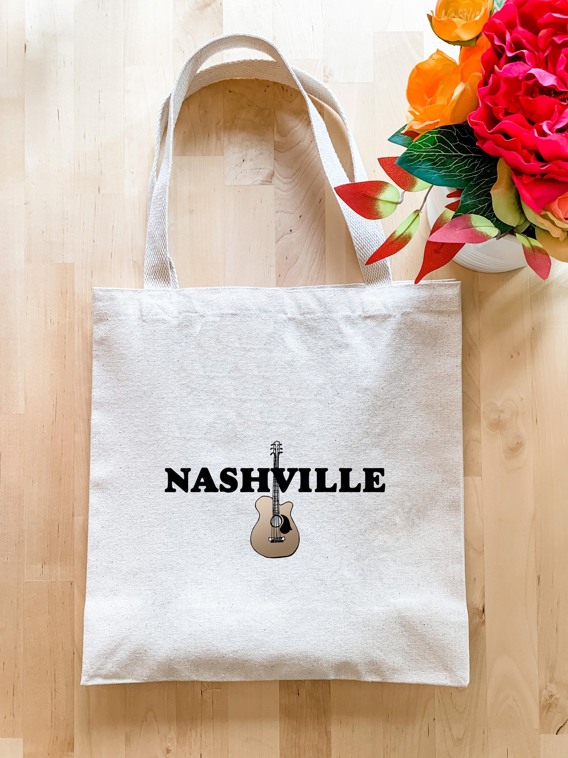 a white bag with nashville on it next to a vase of flowers