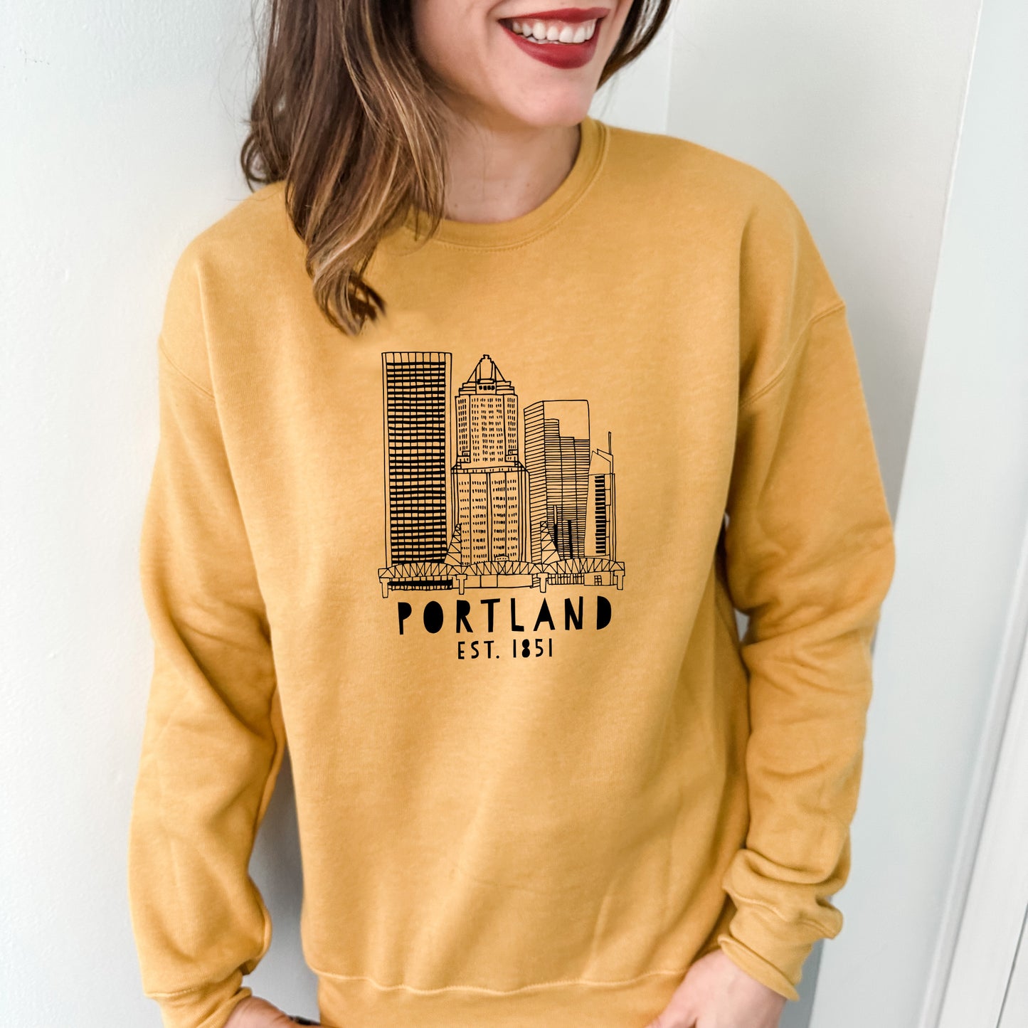 a woman wearing a yellow sweatshirt with a picture of a city on it