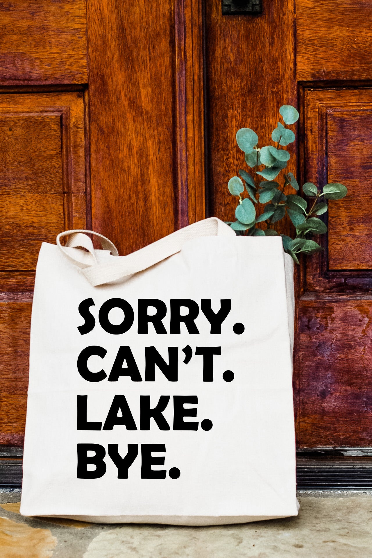 a white tote bag sitting on top of a wooden door