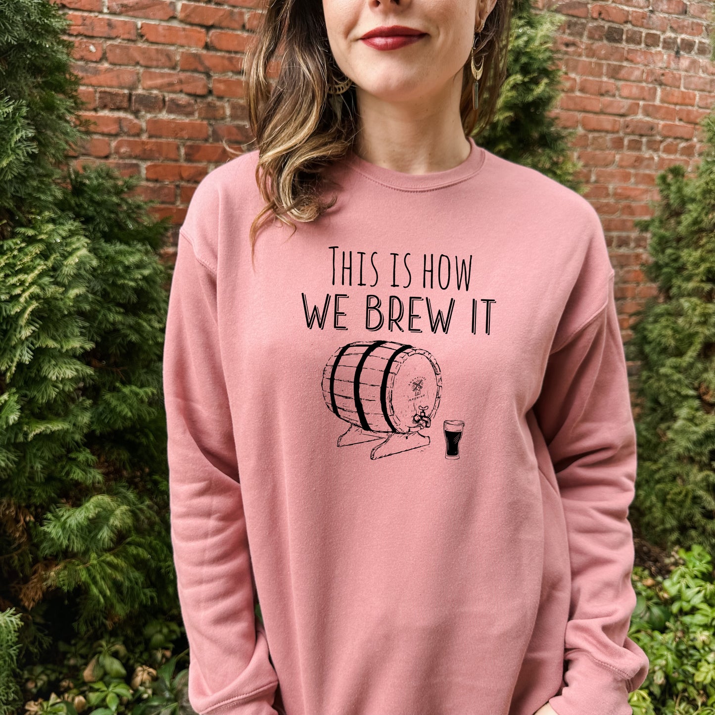 a woman wearing a pink sweatshirt that says, this is how we brew it