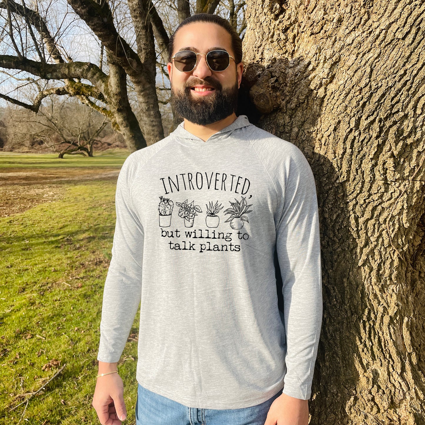 a man standing next to a tree wearing sunglasses