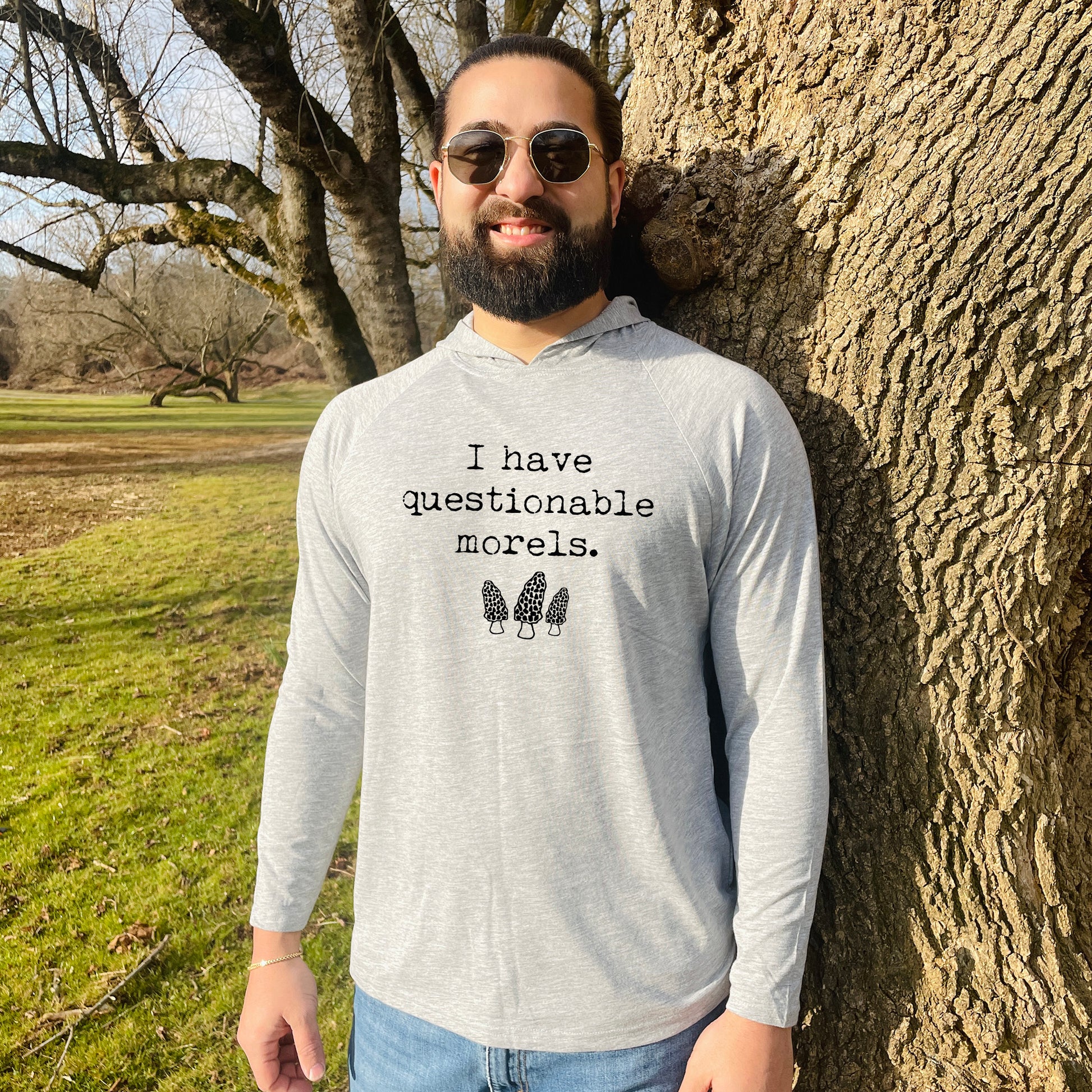 a man standing next to a tree wearing sunglasses