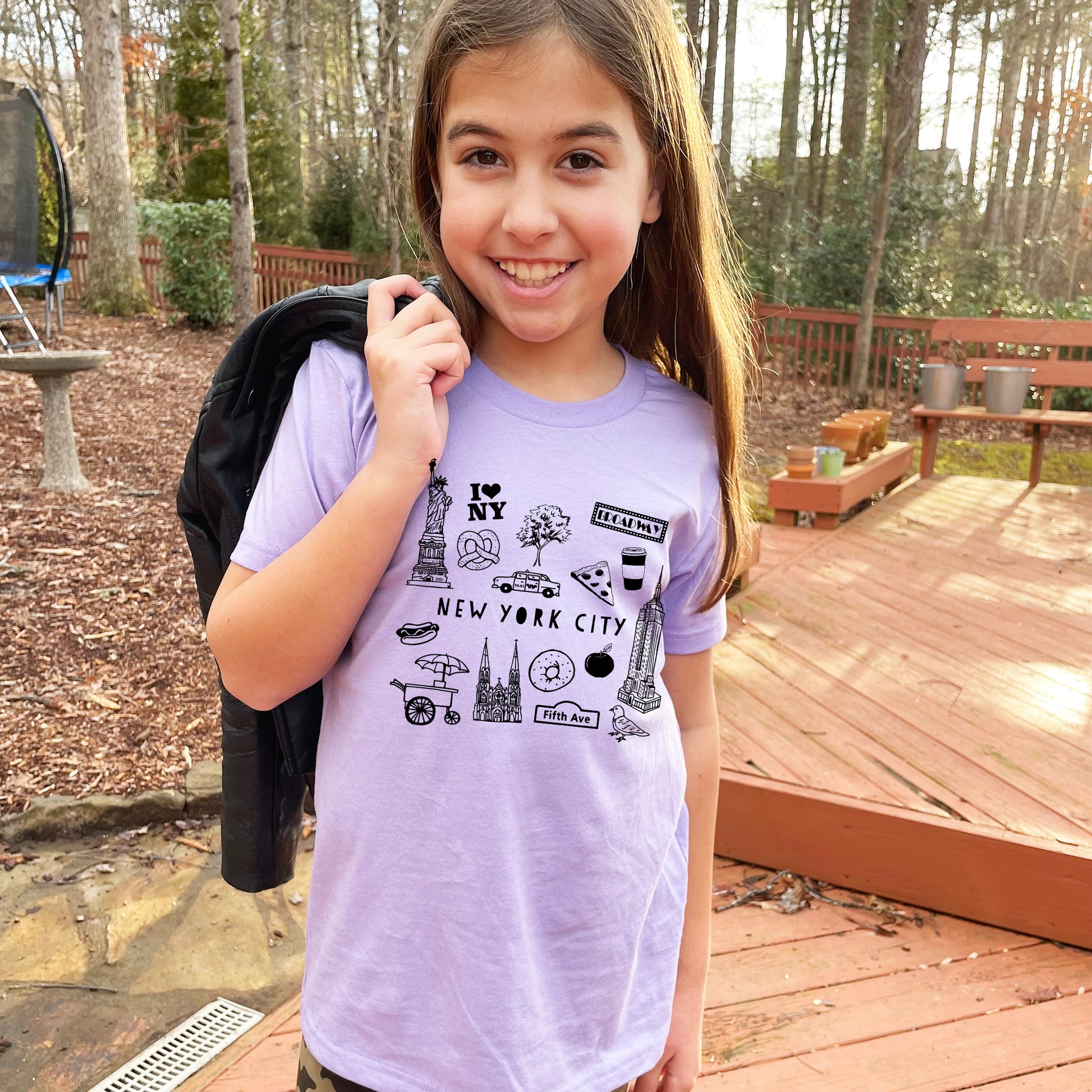 a young girl holding a backpack and smiling