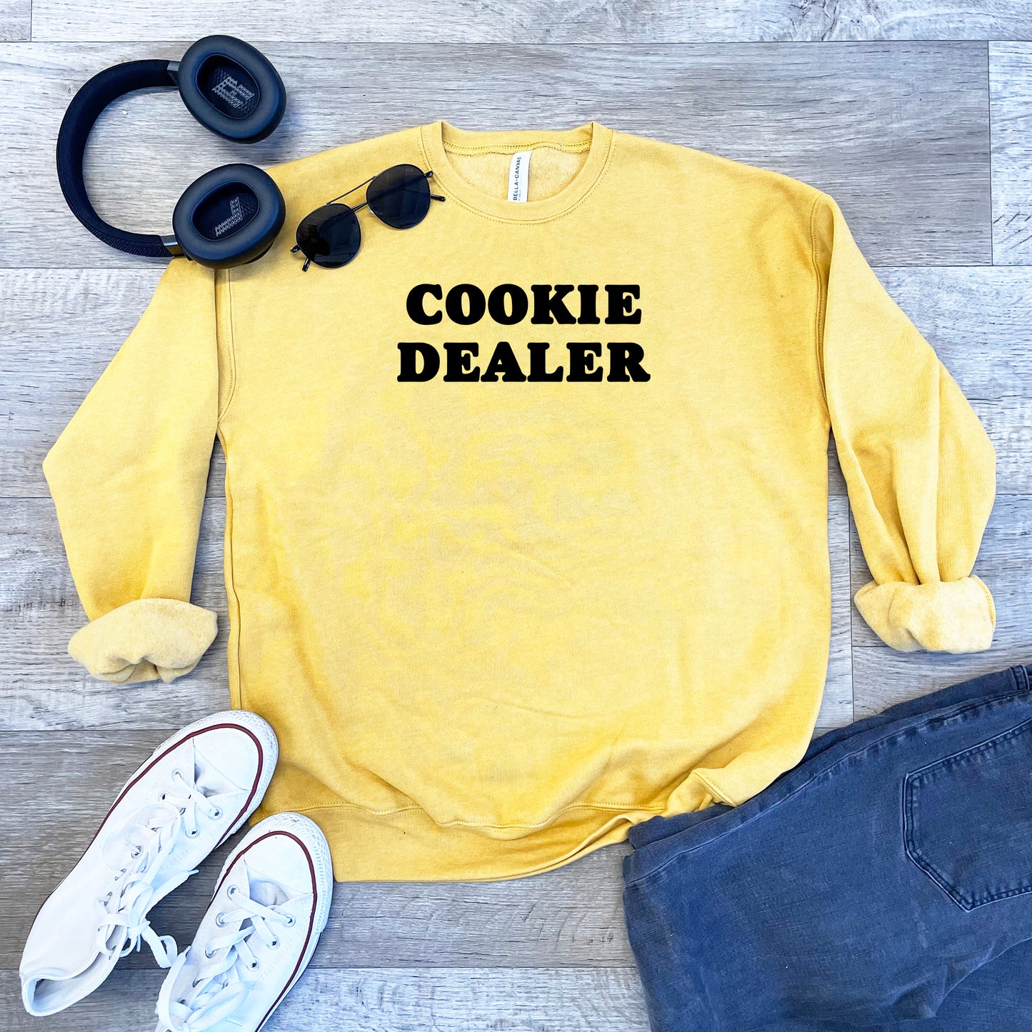 a sweater that says cookie dealer next to headphones