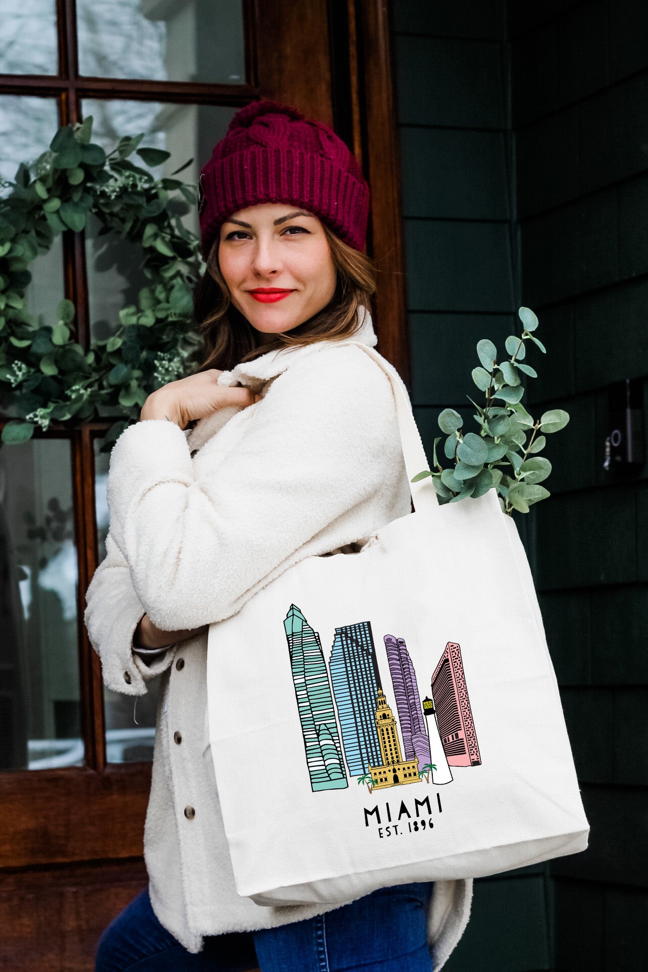 a woman carrying a white bag with a picture of a city