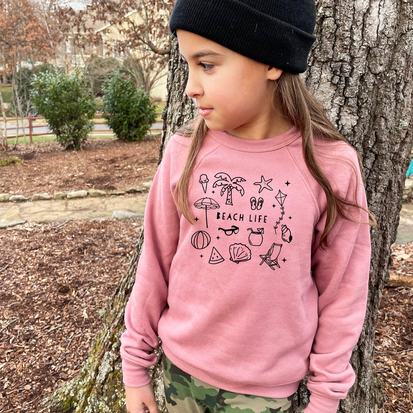 a little girl standing next to a tree