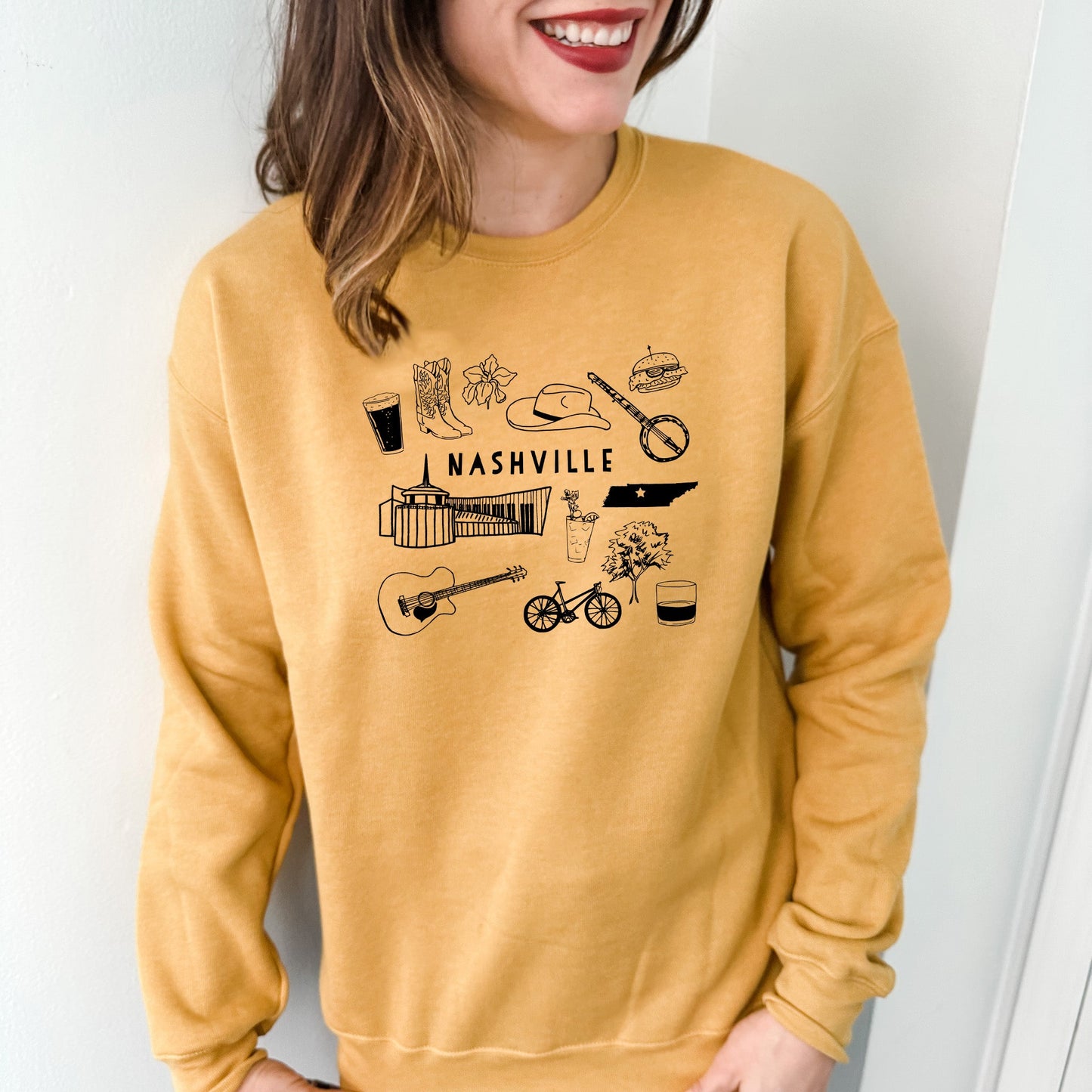 a woman wearing a yellow sweatshirt with the words nashville on it