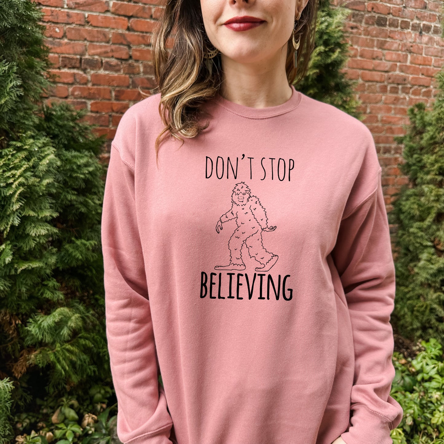 a woman wearing a pink sweatshirt that says, don't stop believing