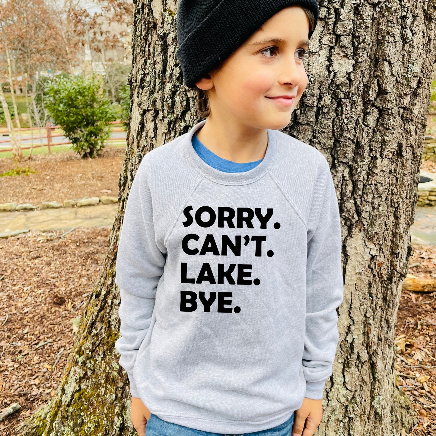 a young boy standing in front of a tree