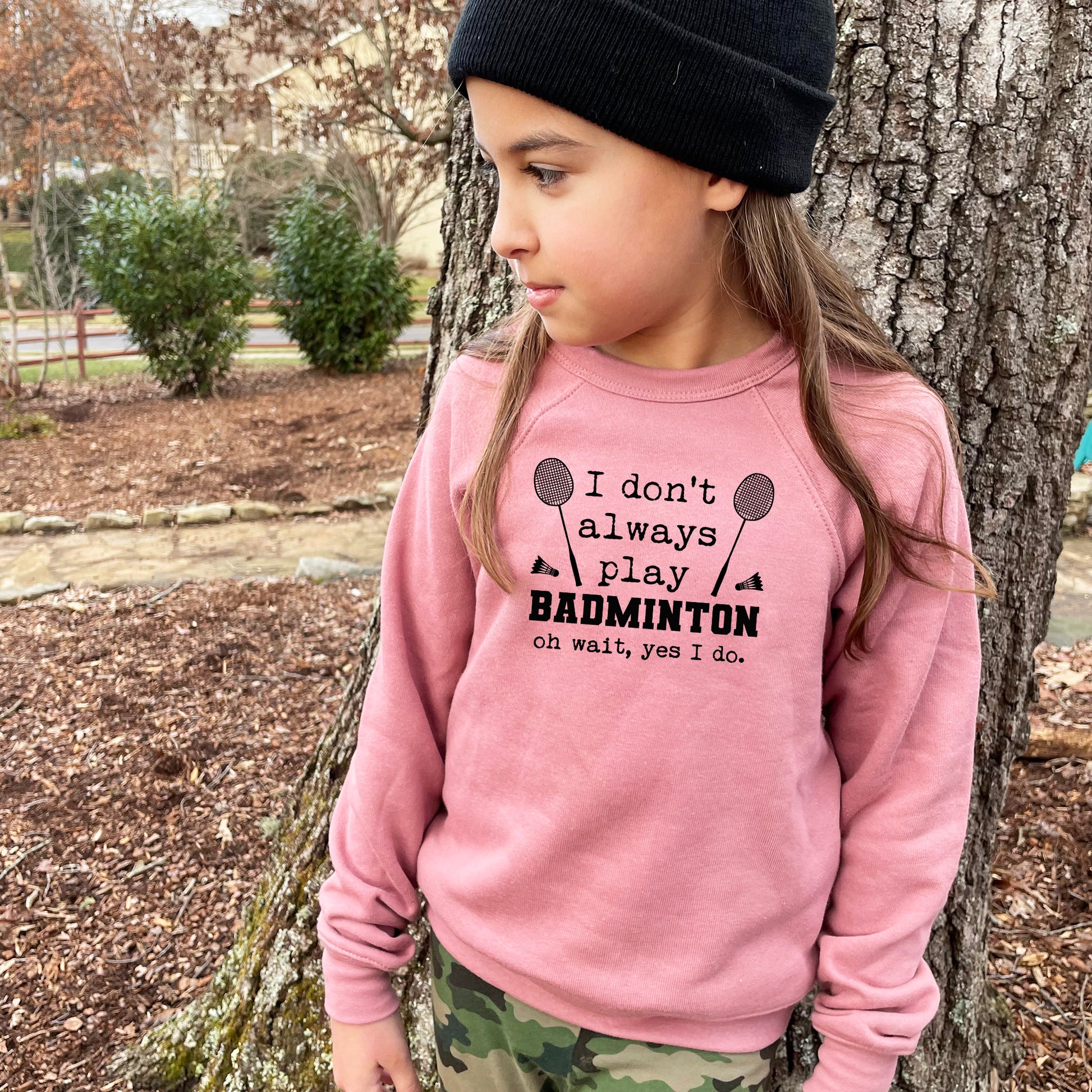 a little girl standing next to a tree