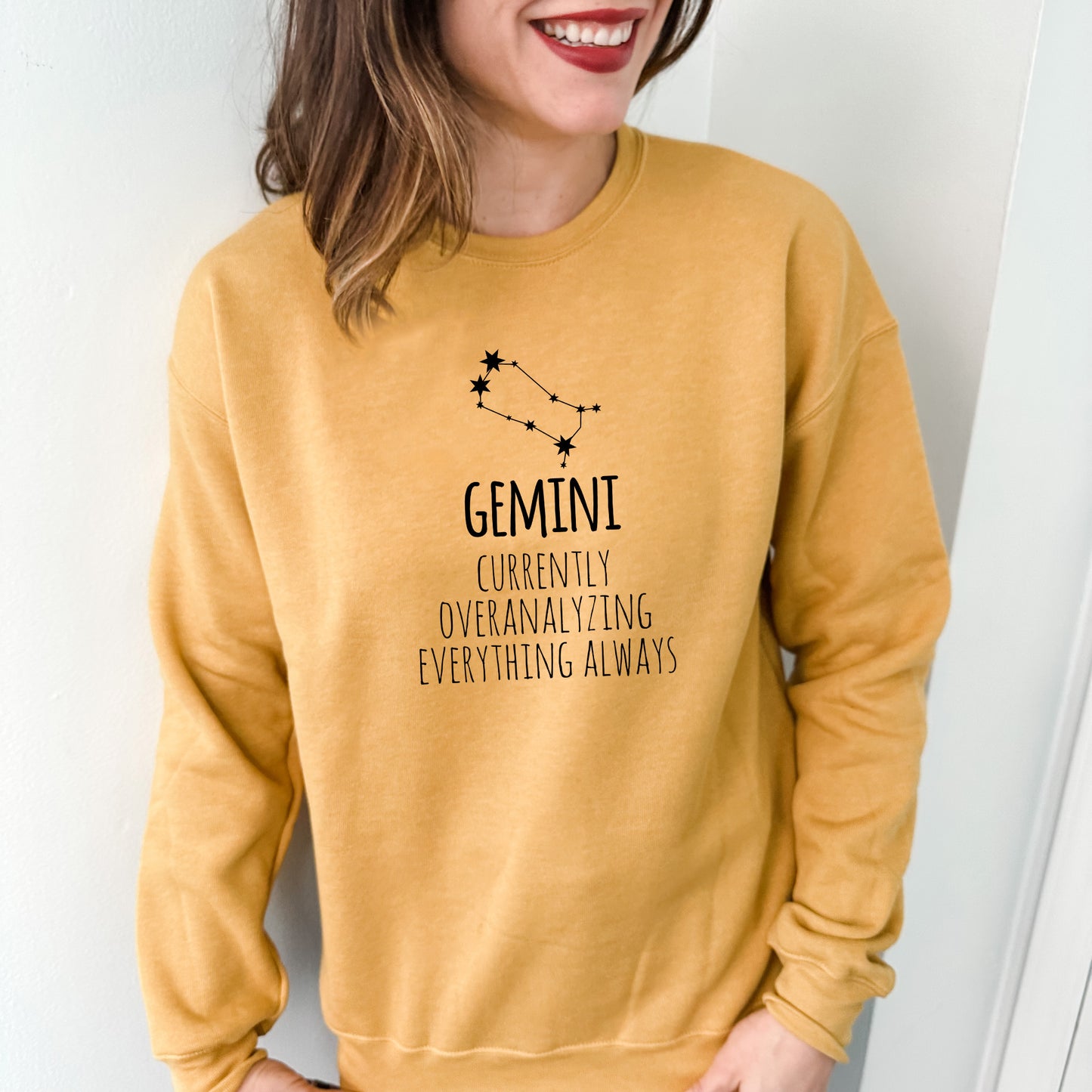 a woman wearing a yellow sweatshirt with a zodiac sign on it