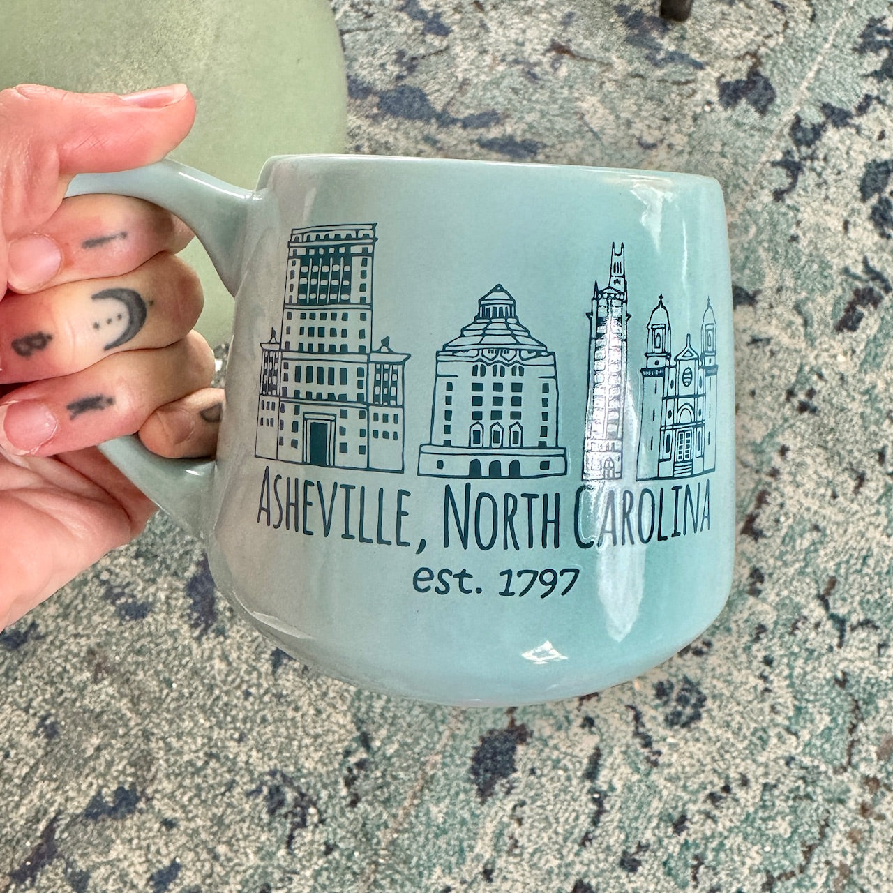 a person holding a coffee mug with a picture of a city on it