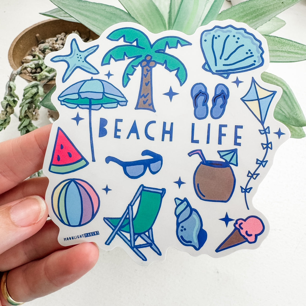 a person holding a sticker that says beach life