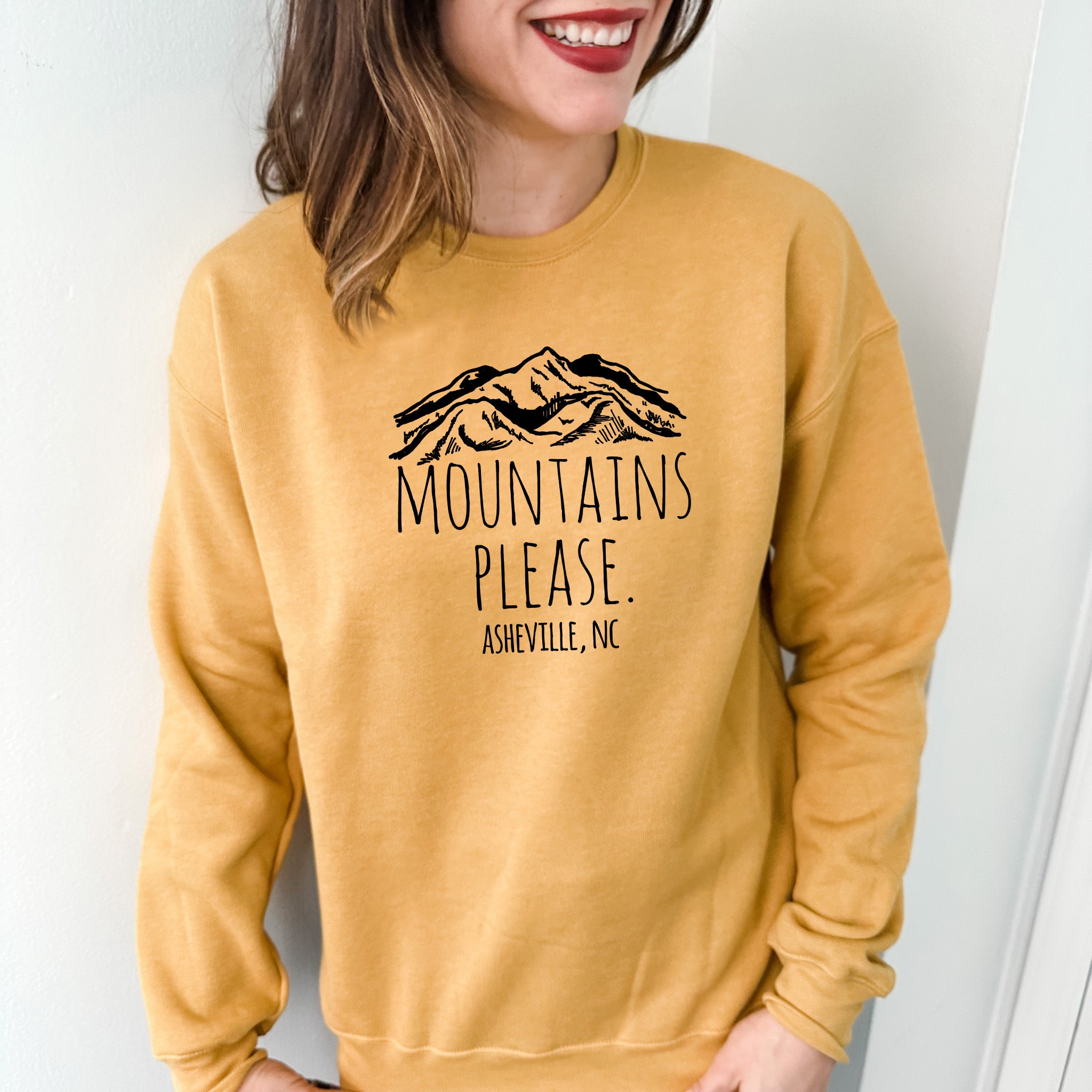 a woman wearing a yellow sweatshirt with mountains please on it
