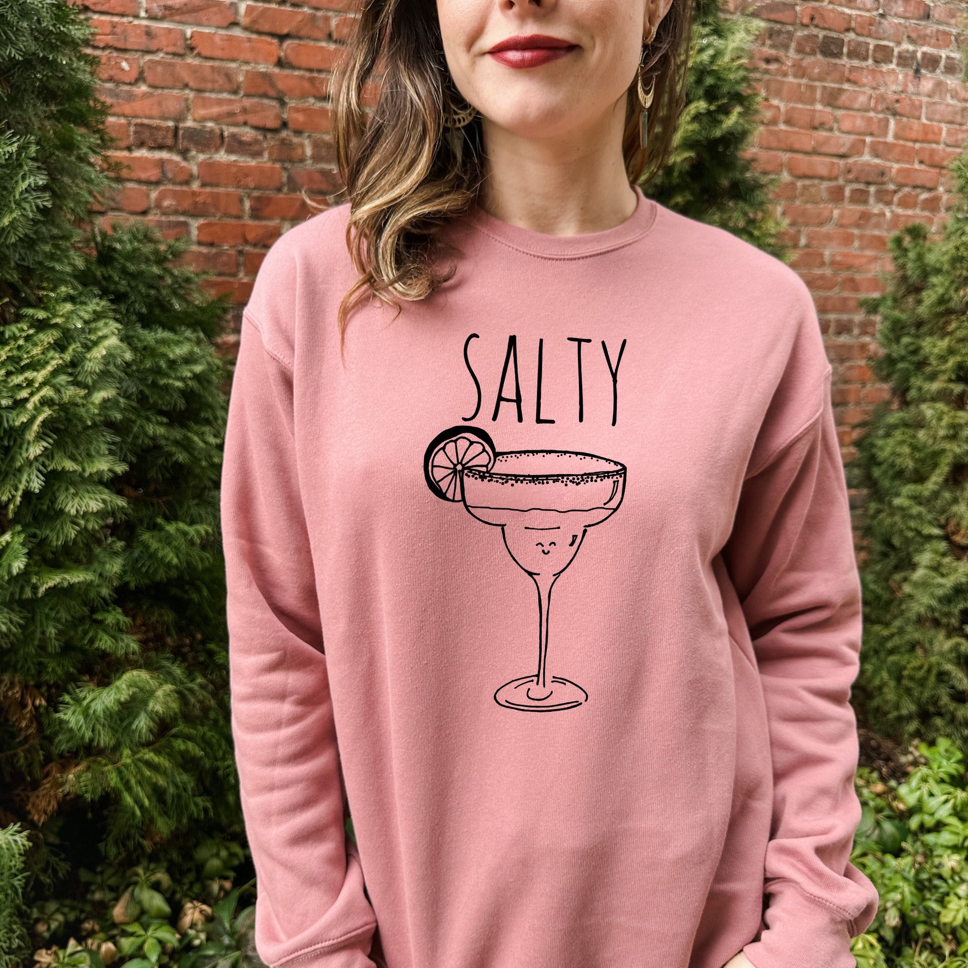 a woman wearing a pink sweatshirt that says salty