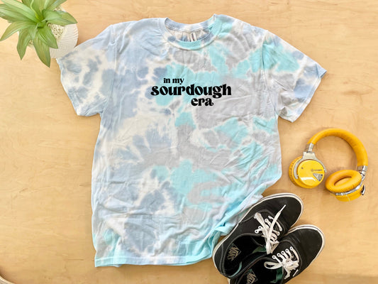 a tie dye shirt that says in my scarborough era next to a pair of head