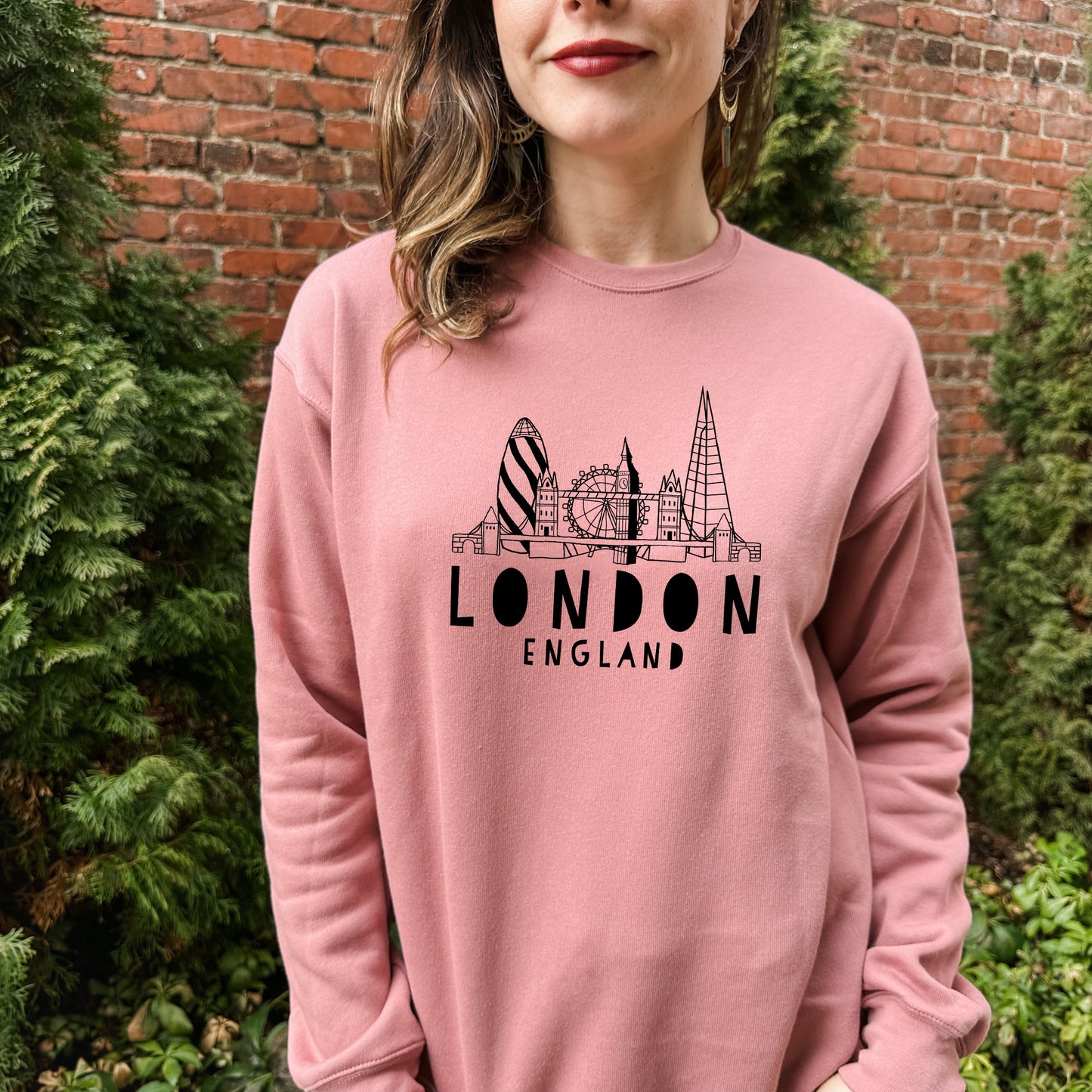 a woman wearing a pink london england sweatshirt