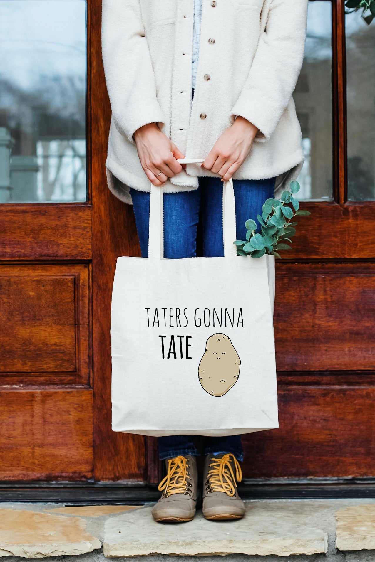 a woman holding a tote bag that says tater's gonna tater