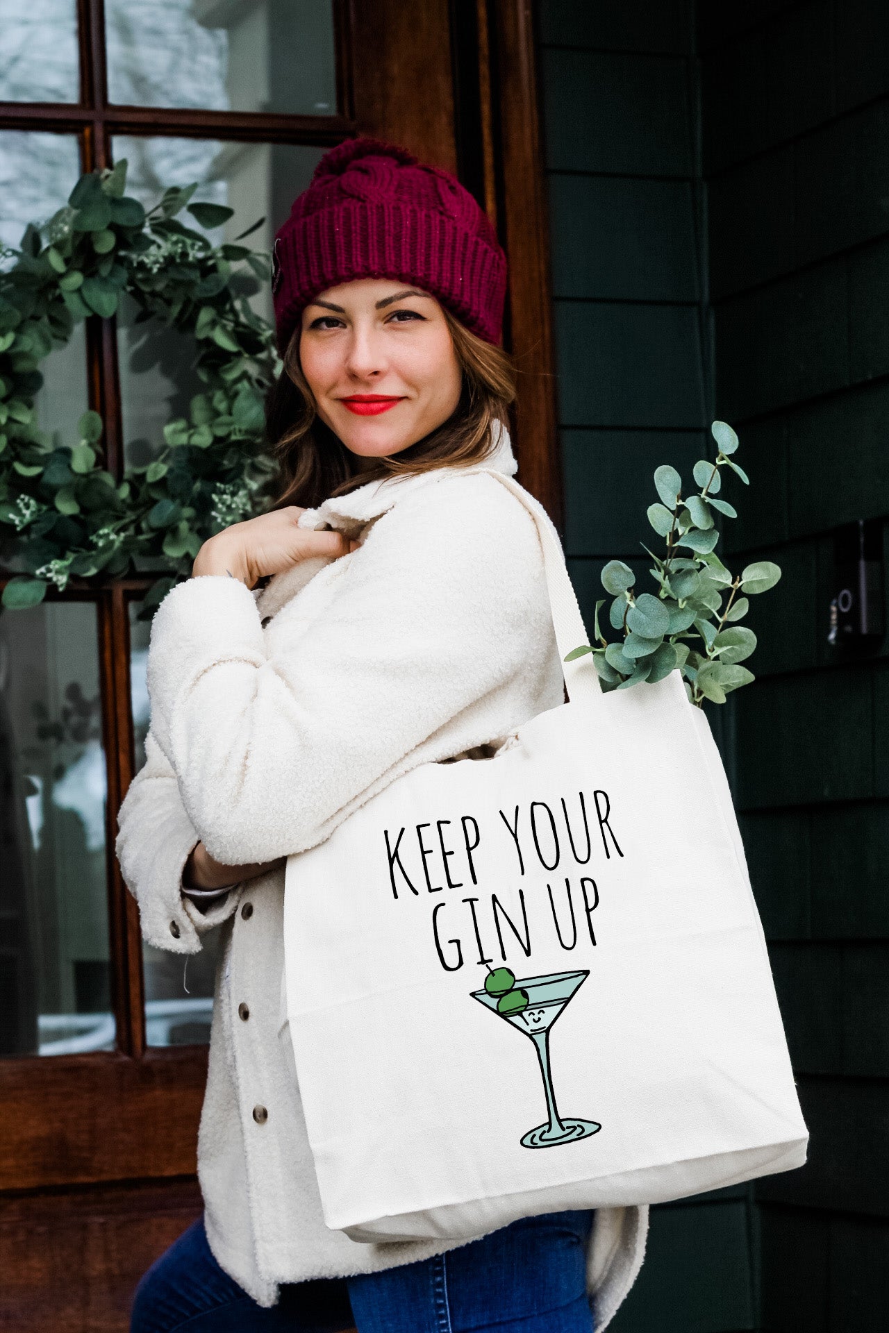 a woman carrying a white tote bag that says keep your gin up