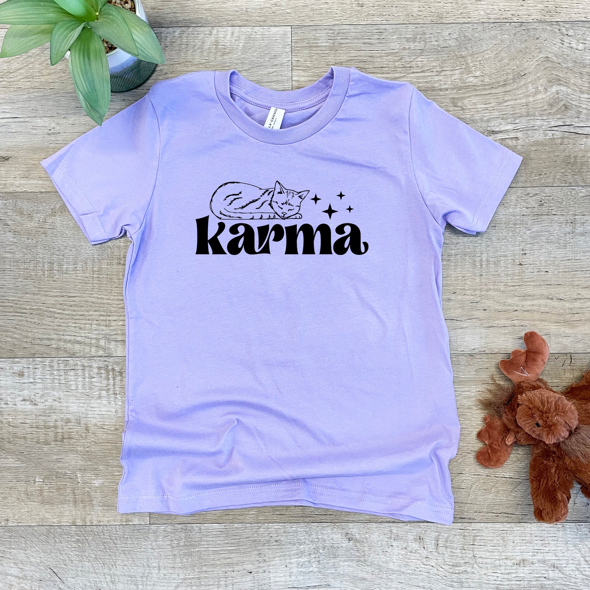 a purple shirt with the word karmia on it next to a teddy bear