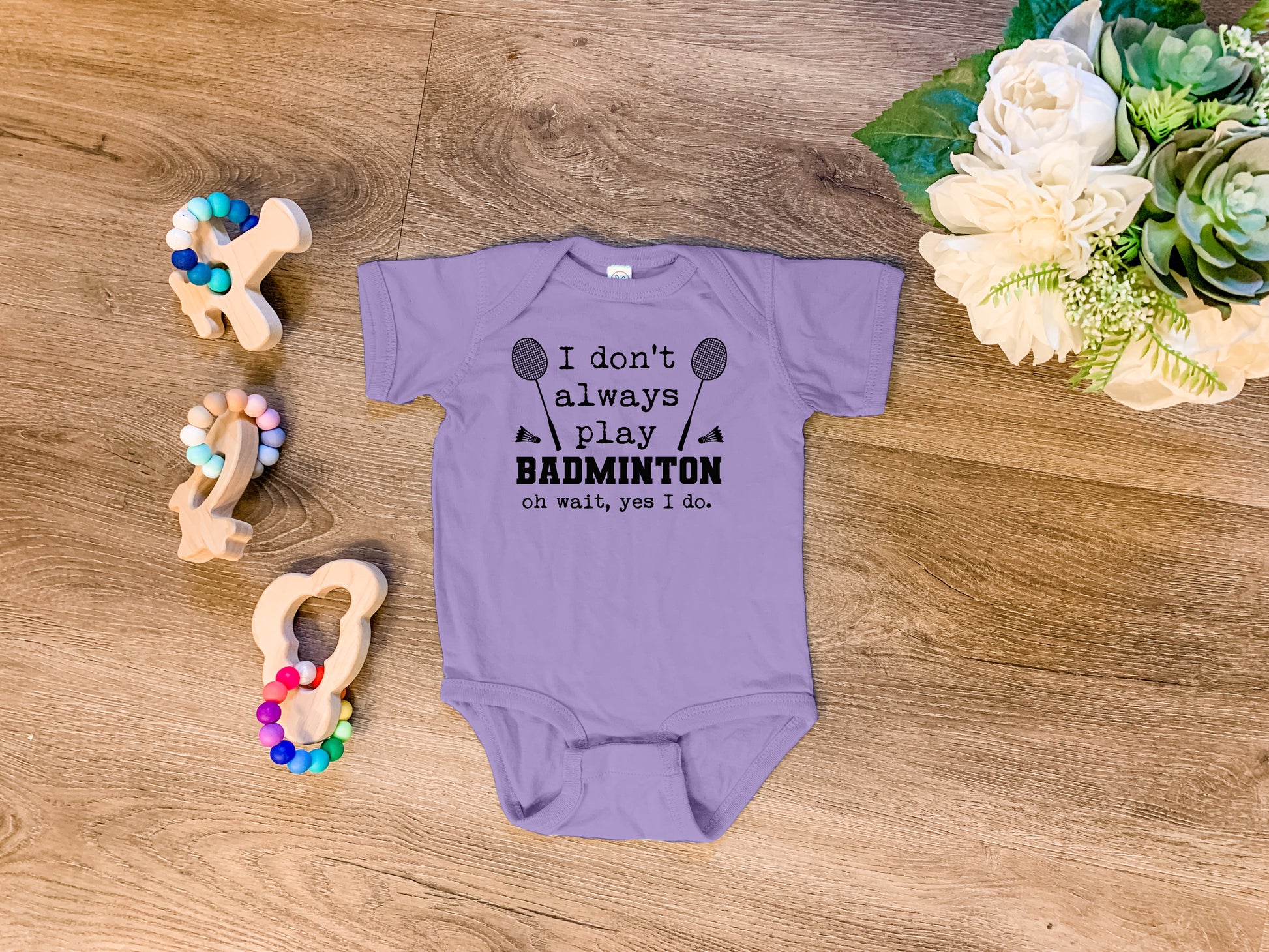 a baby bodysuit sitting on top of a wooden floor