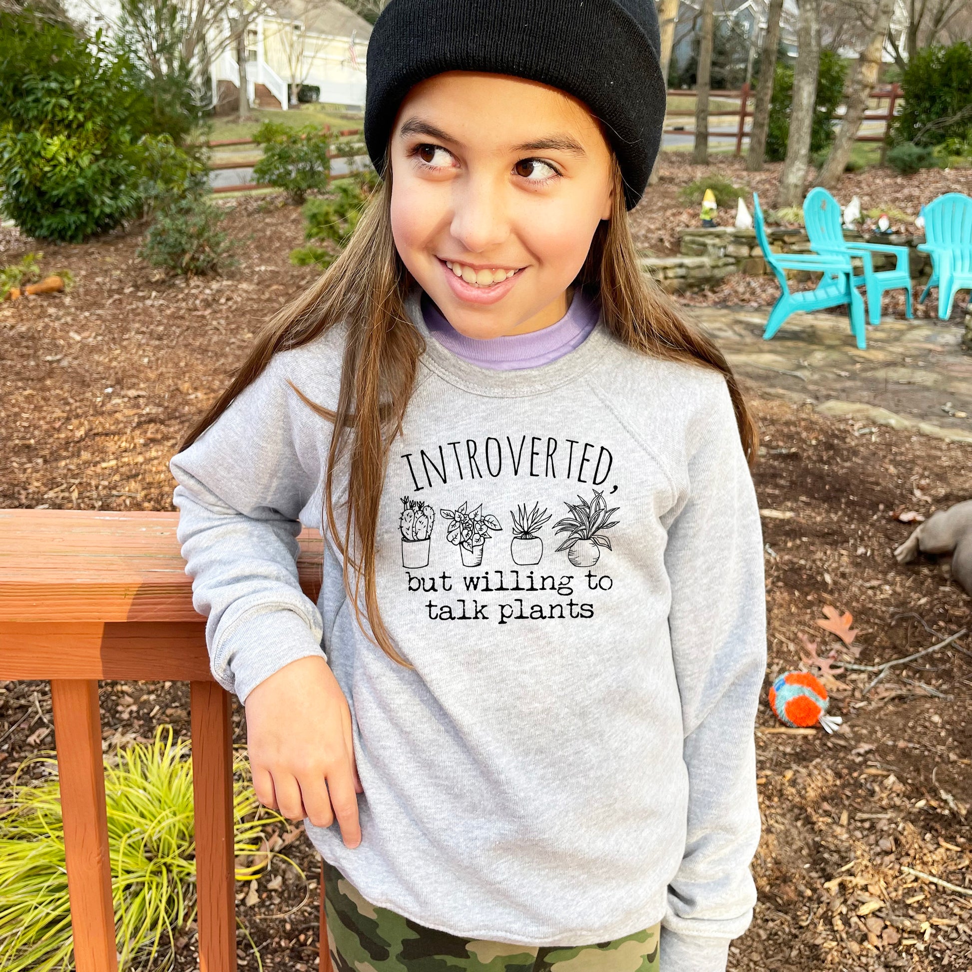 a young girl wearing a hat and a sweatshirt