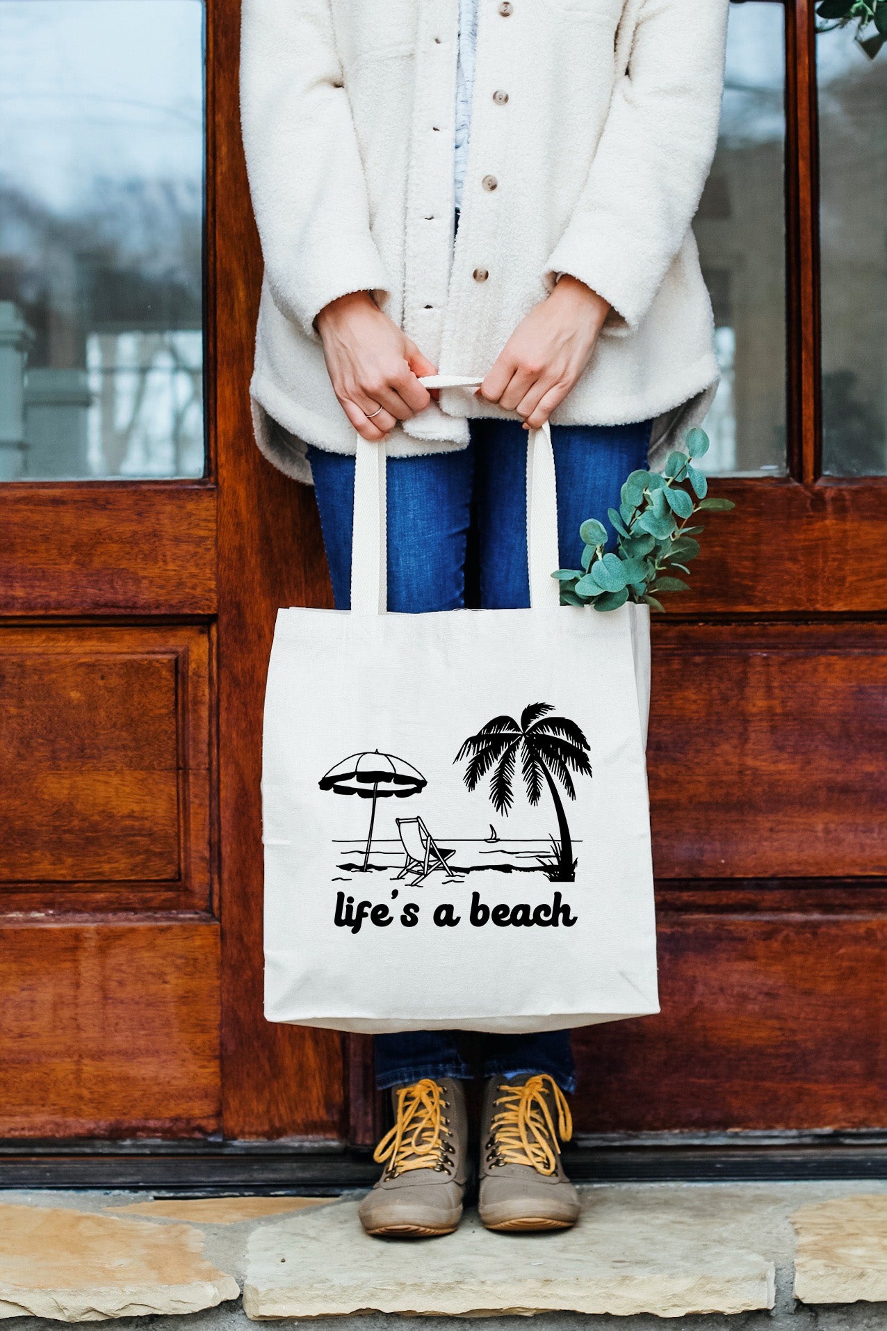 a woman holding a bag that says life's a beach