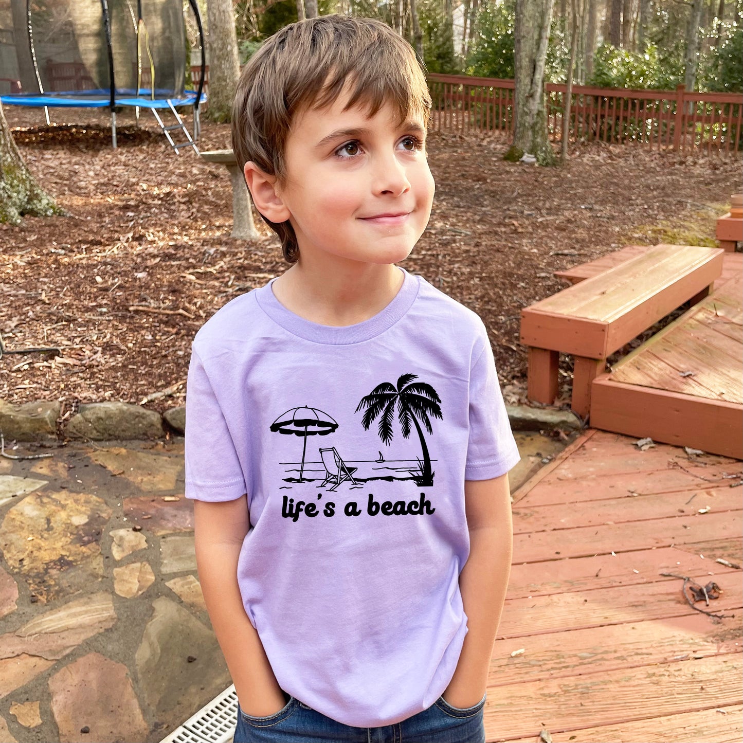 a young boy standing on a wooden deck