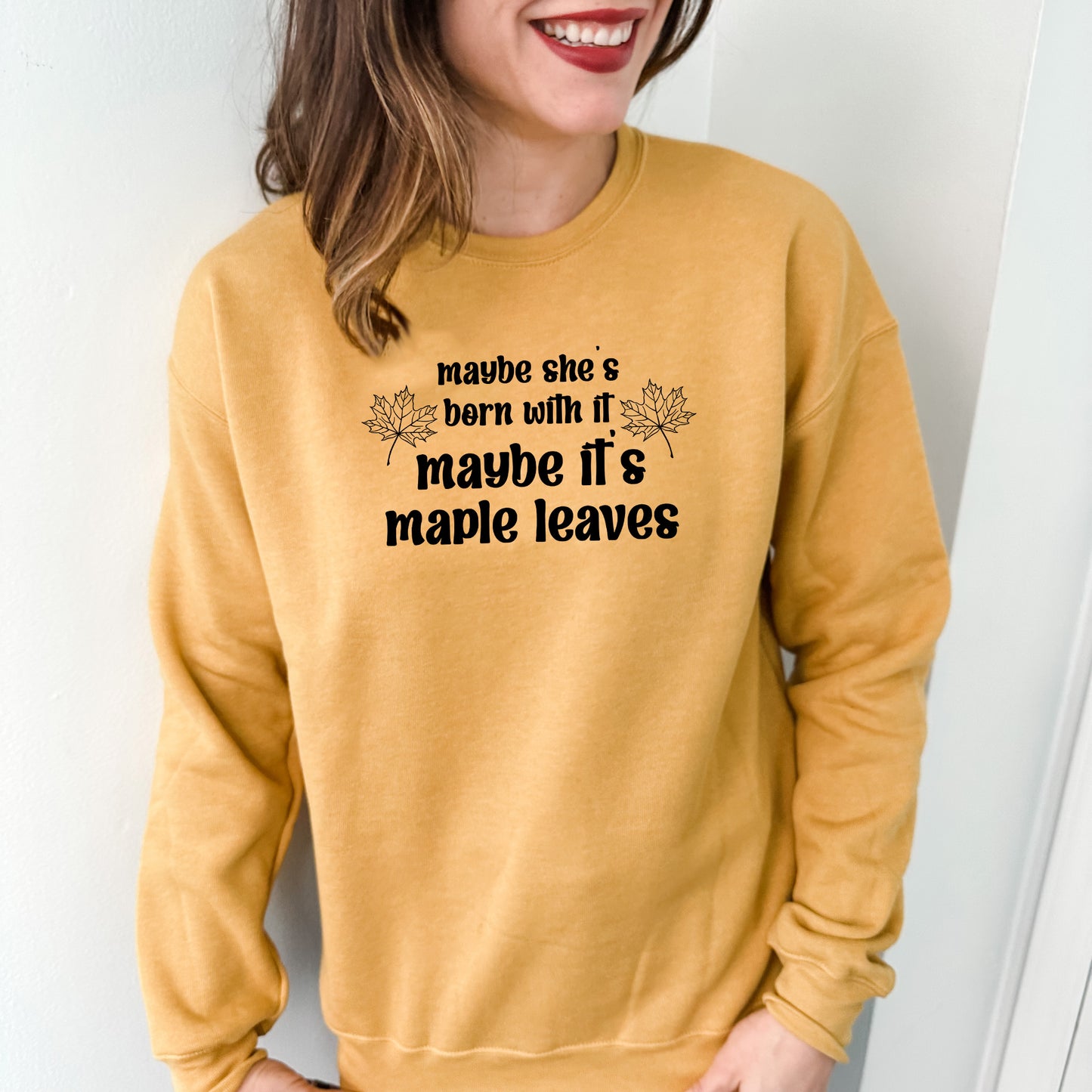 a woman wearing a sweatshirt that says made she's born with maple leaves