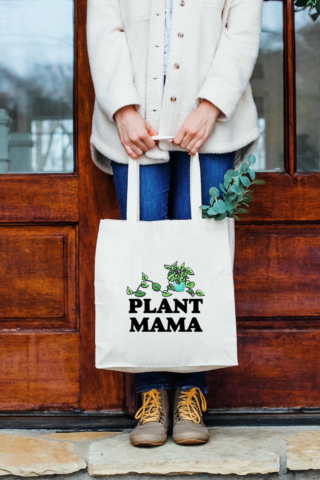 a woman holding a plant mama bag in front of a door